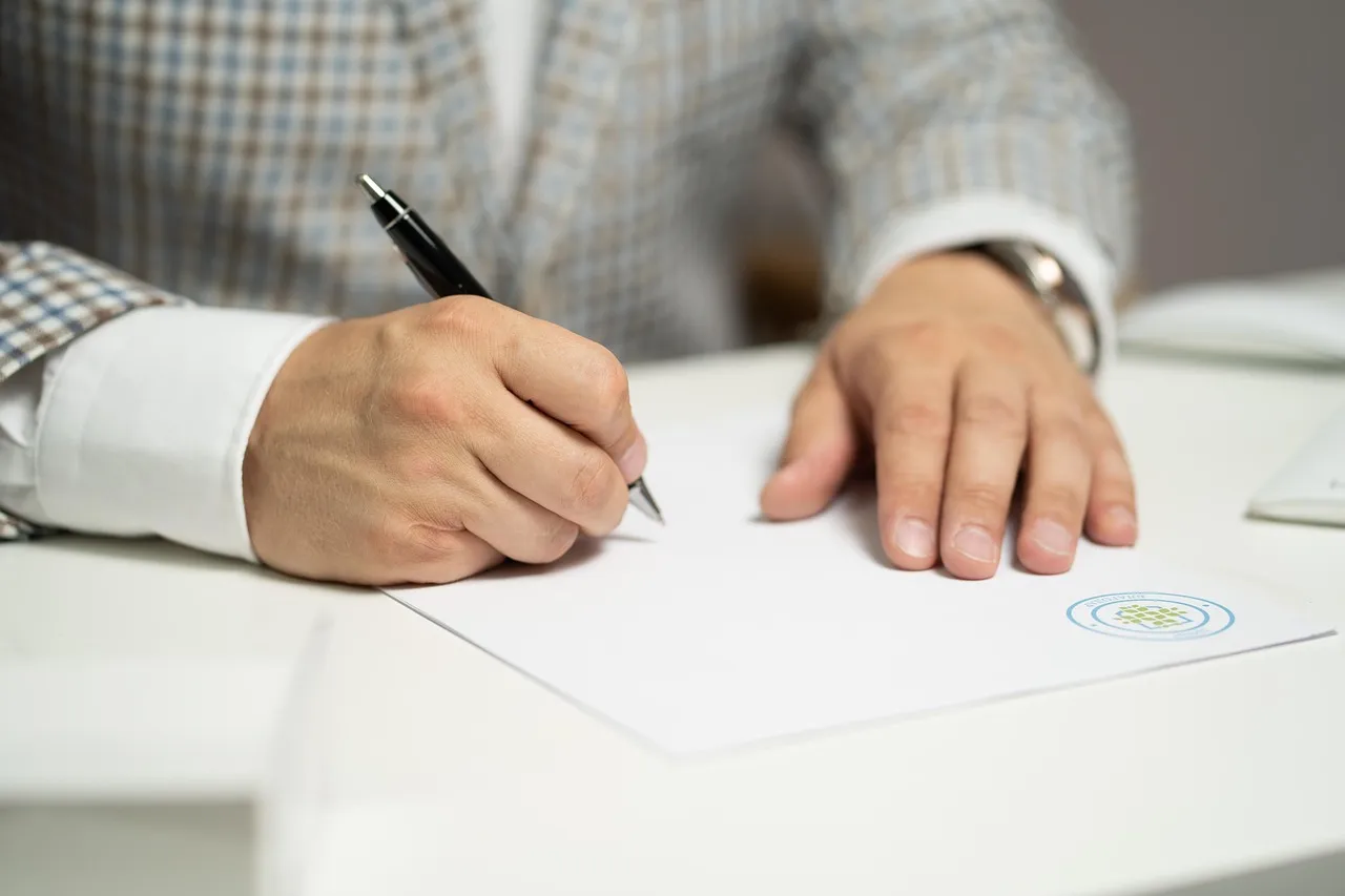 Mains d'une personne remplissant des documents administratifs pour l'accompagnement des familles.
